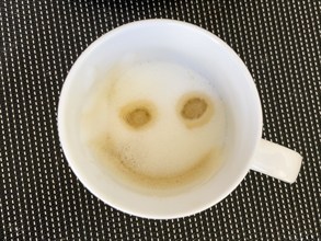 Coffee drink cappuccino with milk foam decorated to smile like emoji smiley, international