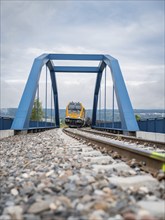 Railway train crossing a blue bridge on a cloudy day, track construction, rail delivery for Hermann