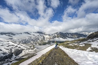 Mountaineer photographed on hiking trail, mountain landscape with snowfields, summit Hoher Weißzint