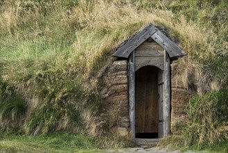 Traditional turf house with wooden door and grass sod roof, replica of a Viking longhouse, home of