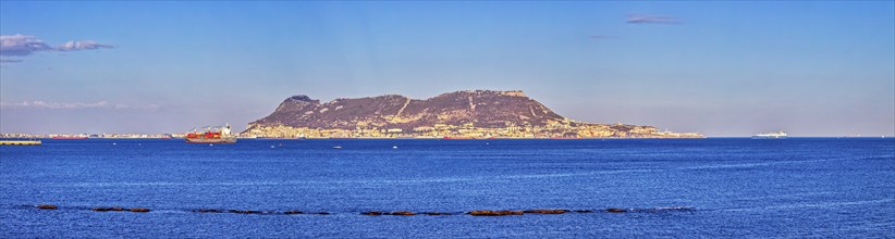 Clear sea with an island in the background and passing ships under a blue sky, Algeciras