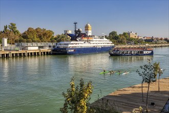 Boats on a river with a large ship near an urban environment, Seville