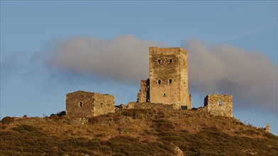 The ruins of an ancient castle stand majestically on a mountain ridge at dusk, residential tower on