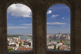 Budapest city skyline with Danube river and Hungarian parliament through stone arches in summer,