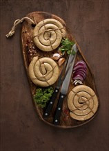 Raw spiral sausages, on a wooden board, top view, with spices, no people