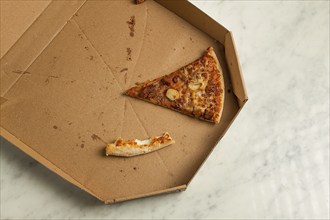 Pizza box, on the table, with one piece and a crust, leftovers, top view, no people