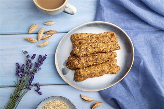 Crumble cookies with seasme and almonds on ceramic plate with cup of coffee and blue linen textile