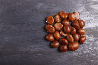 Pile of sweet chestnuts on black wooden background with copy space, top view