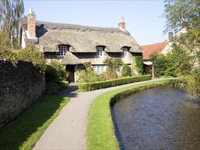 Thatched cottage by stream, Thornton le Dale, Yorkshire, England, United Kingdom, Europe