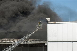 Firefighters in protective clothing in aerial work platform, aerial platform fighting fire in an