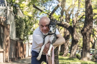 Horizontal portrait of a greyhound dog hugged by its owner in the sunlight, enjoying a walk in the