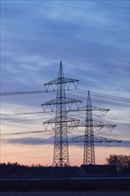 Electricity pylons and power lines in the sunset in Bohmte, Osnabrück district, Lower Saxony,