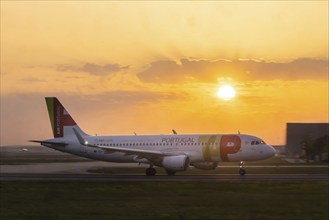 Aircraft Airbus A320-200 of the airline Air Portugal shortly in front of take-off at sunrise,