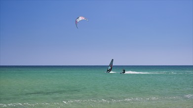 A person windsurfing in a clear blue sea under a sunny sky, surfers paradise, kitesurfer,