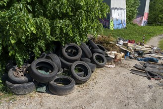 Illegally disposed waste, car tyres, building rubble, household waste, clothing, on a path next to