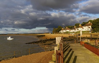 Storm clouds over beach and buildings at Bawdsey Quay, Suffolk, England, UK