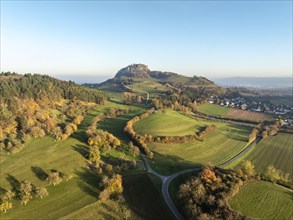 Aerial view of the Hohentwiel volcanic cone in autumn with the castle ruins illuminated by the