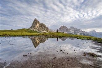 Reflection of the mountains at Passo di Giau, Monte Ragusela, woman with red rucksack, Dolomites,