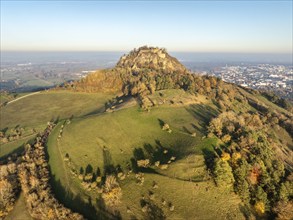 Aerial view of the Hohentwiel volcanic cone in autumn with the castle ruins illuminated by the