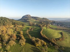 Aerial view of the Hohentwiel volcanic cone in autumn with the castle ruins illuminated by the