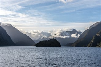 Sun rising over Doubtful Sound, Clouds hanging low on the mountains, South Island of New Zealand