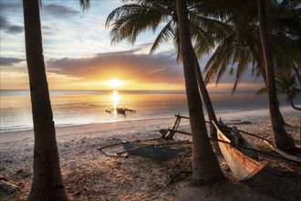 Sunset on a beach in Siquijor with palm trees and Bangka boat