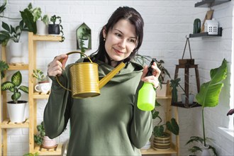 A portrait of a woman looks into the frame with an interior watering can and a spray gun for caring