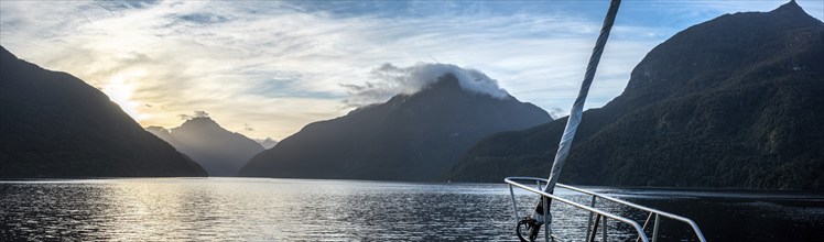 Sun rising over Doubtful Sound, Clouds hanging low on the mountains, South Island of New Zealand