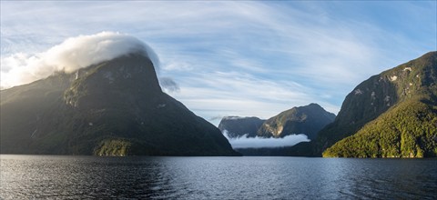 Sun rising over Doubtful Sound, Clouds hanging low on the mountains, South Island of New Zealand