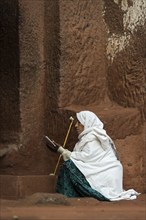 Ethiopian Orthodox woman prays at the entrance to the rock-hewn church of Biete Gabriel-Rufael,