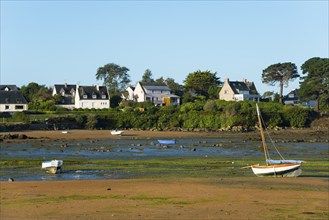 Boats on a sandy strip in front of a coastal town with green vegetation, Trégastel, Tregastel,