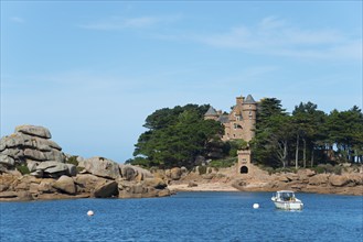 Historic castle on a rocky island surrounded by clear blue sea with a small white boat, granite