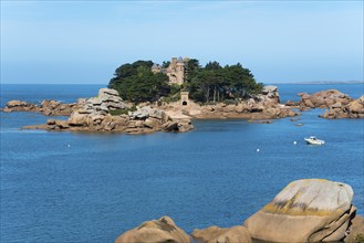 Picturesque island with historic building and rocks, surrounded by deep blue water and sunny skies,