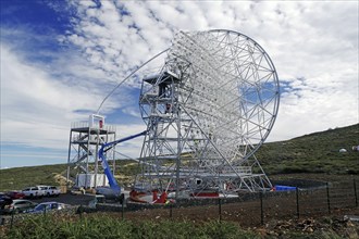 A technical telescope stands in a green landscape under a cloudy sky, Observatory, Roques de los