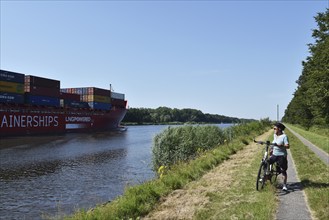 Cyclist and container ship on the Kiel Canal, Kiel Canal, NOK, Schleswig-Holstein, Germany, Europe