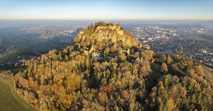 Aerial view of the Hohentwiel volcanic cone with the castle ruins illuminated by the evening sun,