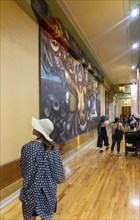 People viewing artwork 'Nueva Democracia' 1944 mural by David Alfaro Siqueiros inside Palacio de