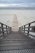 Wooden stairs to the empty beach and sea in the evening