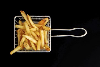 An aerial perspective of a modest basket containing French fries, set against a dark backdrop