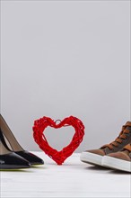 Still life of mens and womens shoes and red heart. Vertical shot copy space