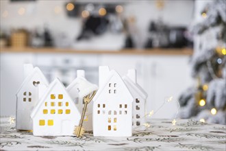 Key and tiny house of a small size on cozy home with Christmas decor on table of festive white