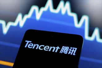 In this photo illustration, the Tencent logo is displayed on a smartphone screen and in the