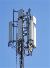 A tall cell tower with multiple antennas against a clear blue sky