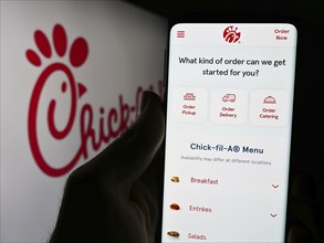 Stuttgart, Germany, 04-08-2024: Person holding cellphone with webpage of US fast food restaurant