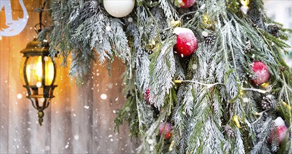 Outdoor Christmas decorations made of natural spruce branches, toys, garlands and a glowing lantern