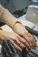 Beauty treatment in a beauty salon, view of the hands of the client and the cosmetologist