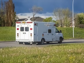 A rear view of a plain white ambulance traveling on the road