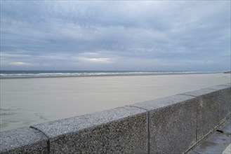 Wall in front of the empty beach and sea in the evening