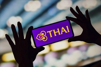 In this photo illustration, the Thai Airways International logo is displayed on a smartphone screen