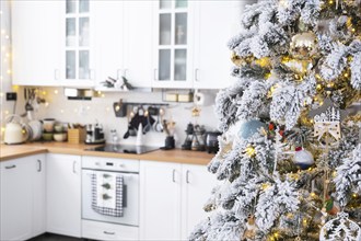 Festive Christmas decor in white kitchen, modern rustic interior with a snowy Christmas tree and